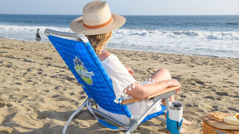 A woman at the beach sitting in a Tommy Bahama beach chair