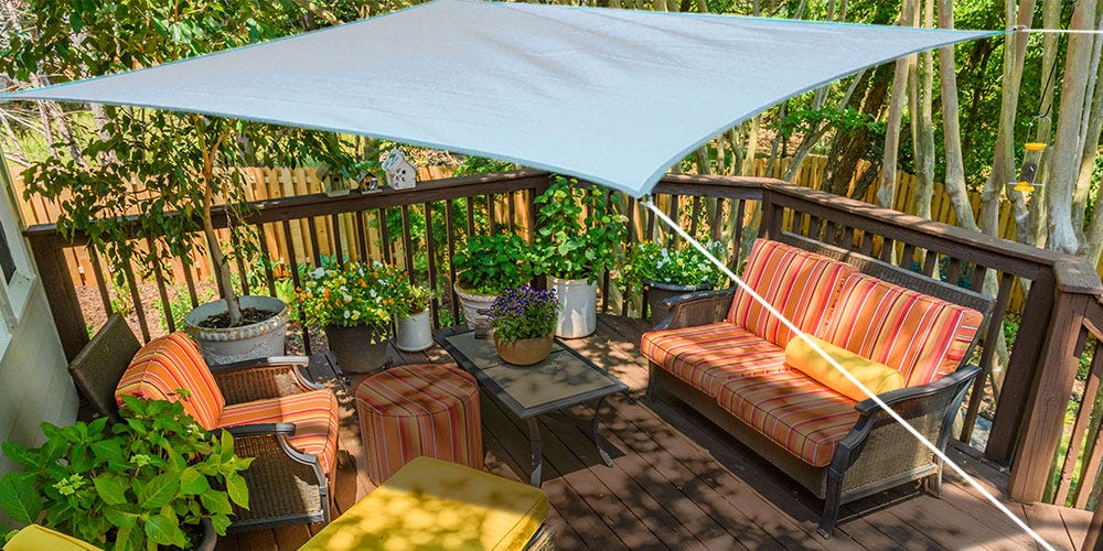backyard ideas include a shade sail over patio furniture